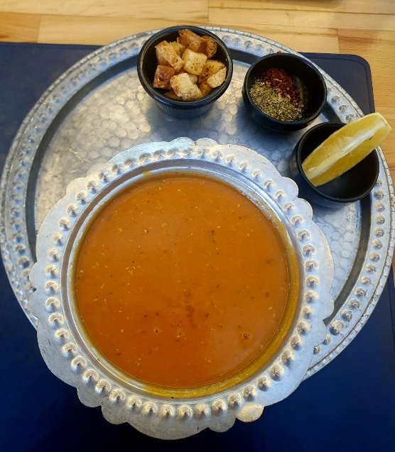 A bowl of traditional Azerbaijani lentil soup with a rich, earthy color, garnished and ready to serve