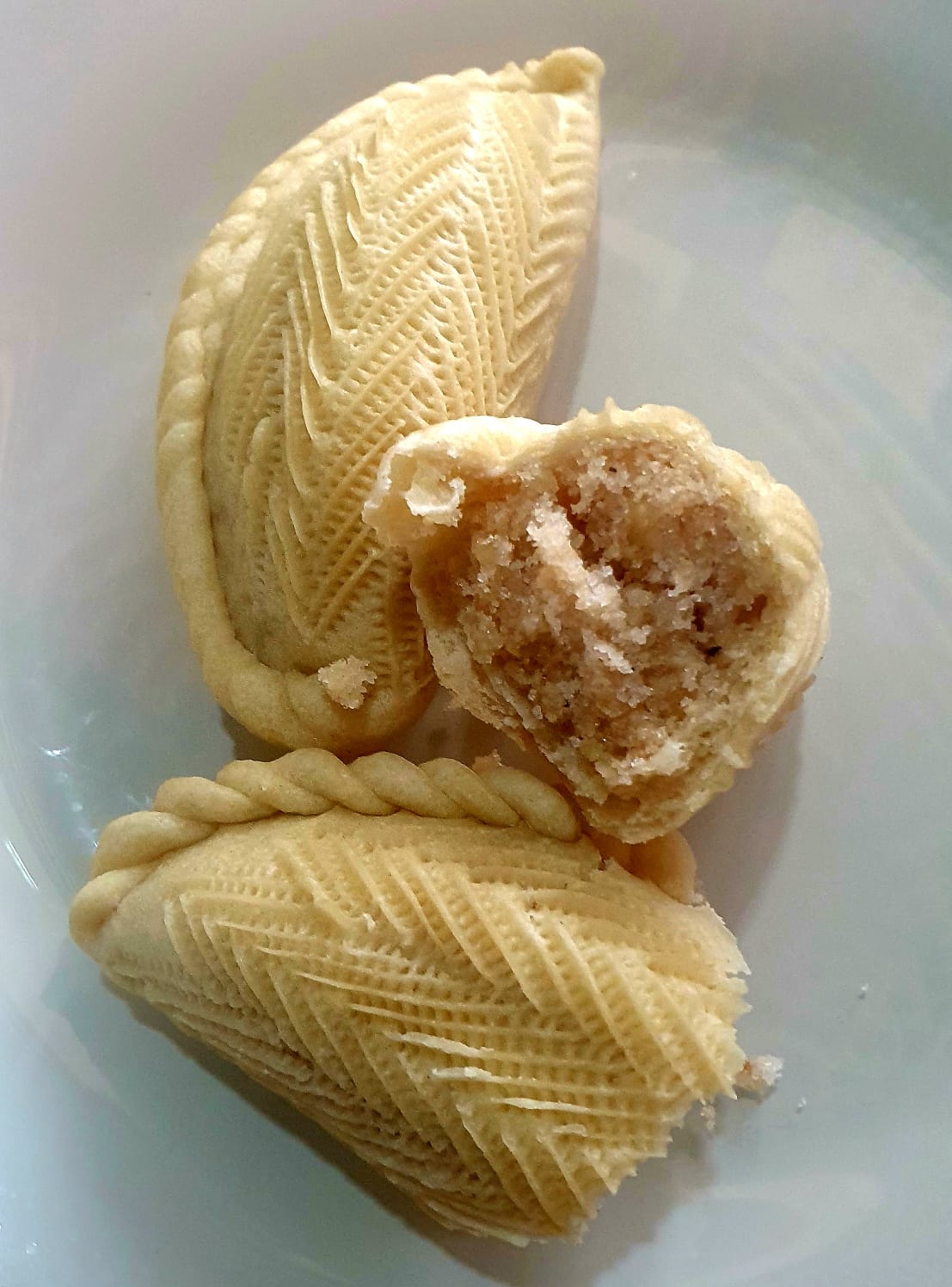 Traditional Azerbaijani shekerbura pastries arranged on a serving platter, featuring crescent-shaped cookies with crimped edges and nut filling, symbolizing the moon during Novruz celebrations