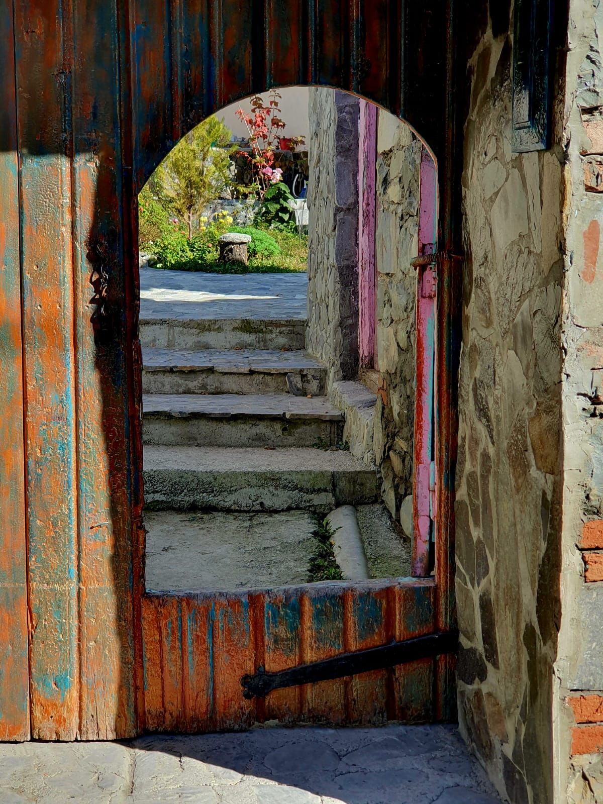 Traditional entrance to a village house in Azerbaijan, featuring an ornate wooden door and decorative archway framed by weathered stone walls