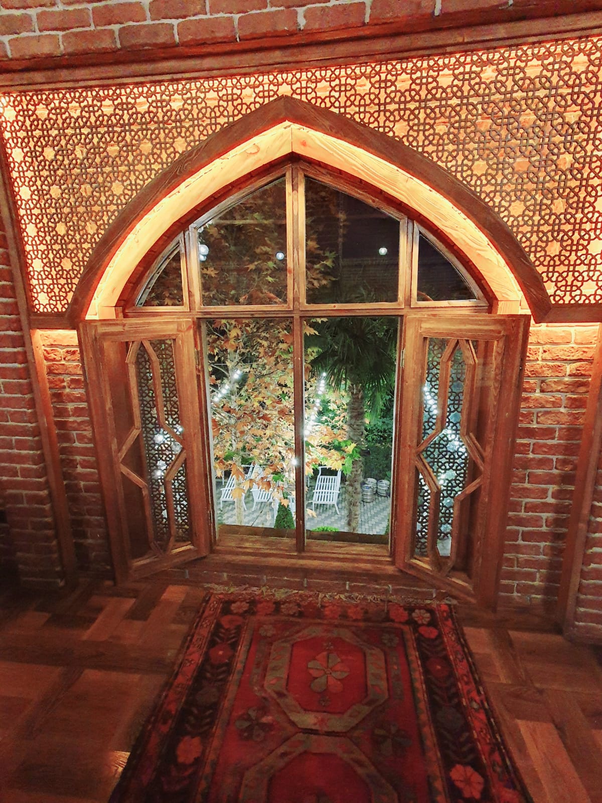 Traditional shebeke stained-glass window in a restaurant in Sheki, Azerbaijan, featuring intricate geometric wooden lattice work filled with colored glass panels and a pointed arch design