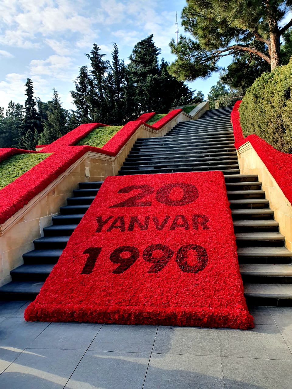 Steps at the January 20th Memorial in Baku covered with red flowers displaying '20 Yanvar 1990' in commemoration of Black January