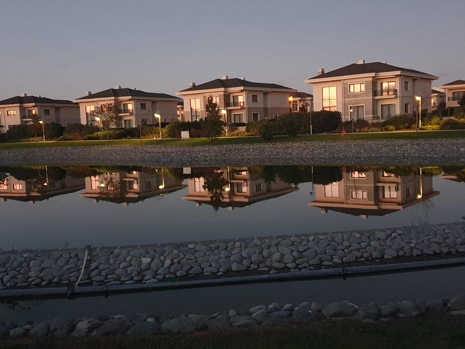 Modern residential villas in Dreamland, Baku, reflected in a decorative pond at dusk