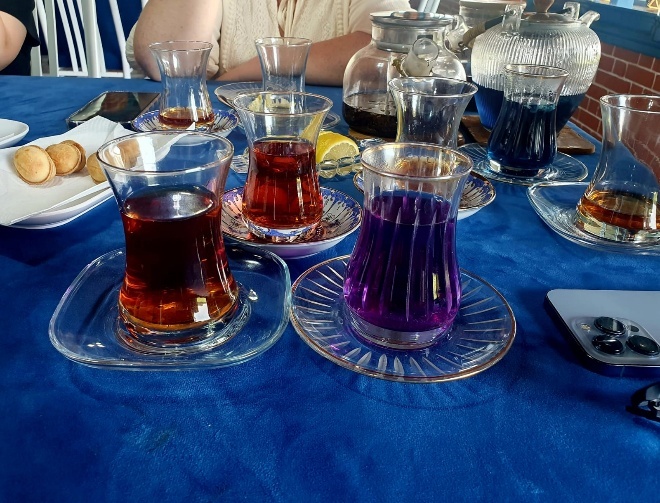 Two armudu glasses filled with tea - traditional amber Azerbaijani tea on the left, and blue butterfly pea flower tea on the right that turns purple when lemon juice is added