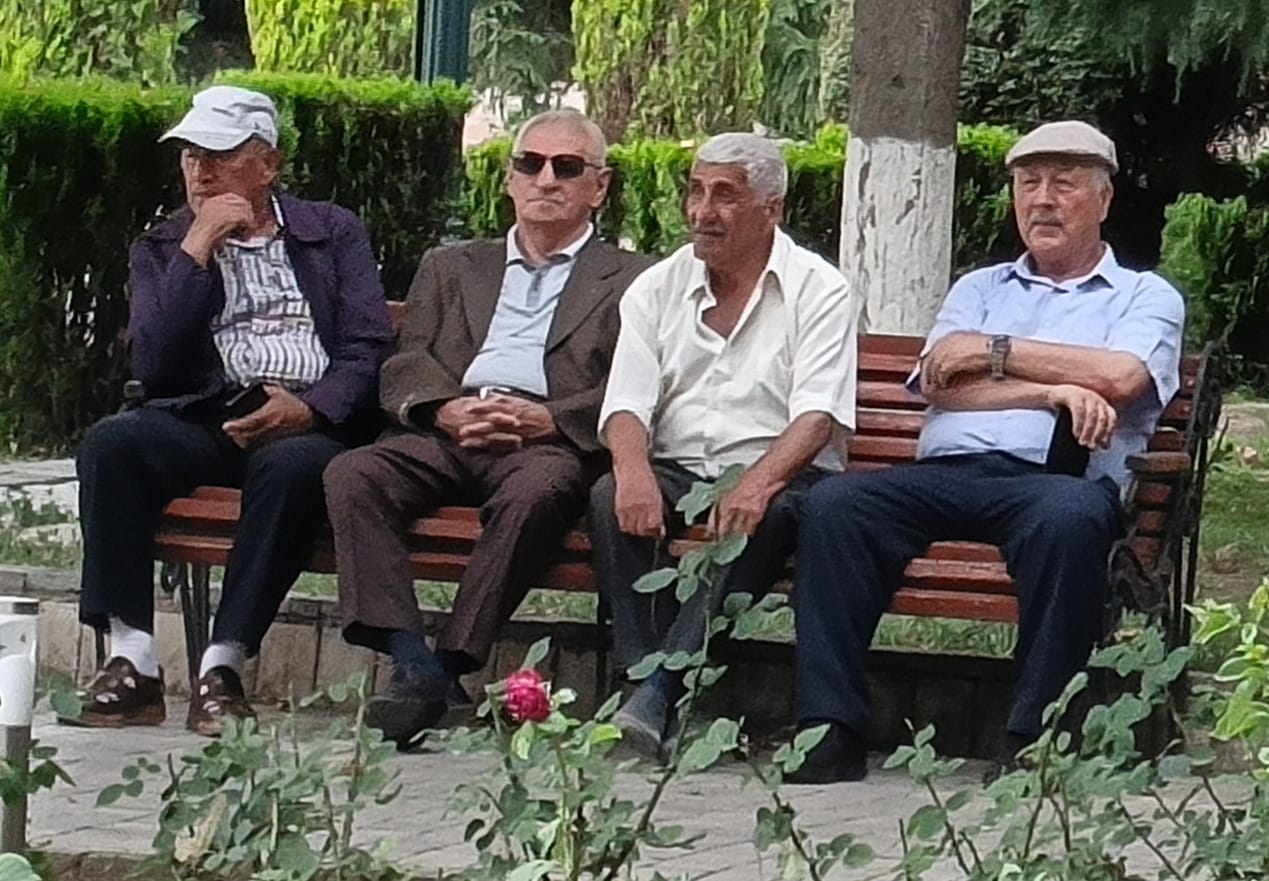 A group of elderly men gathered in a public park in Azerbaijan, sitting and socializing together