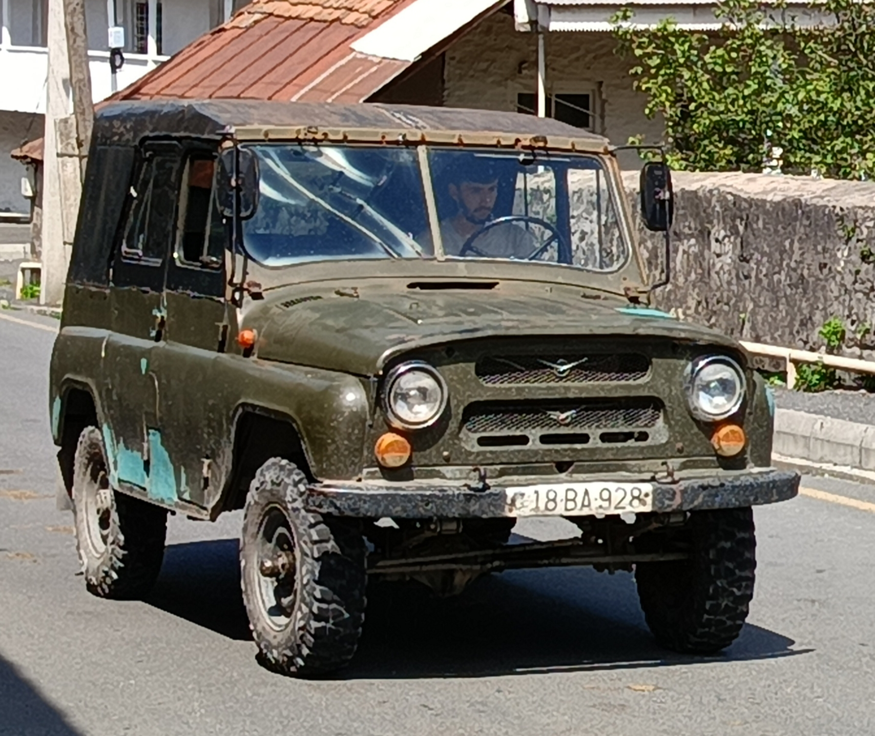 Worn Lada sedan heavily loaded with cargo on its roof rack, parked on an unpaved road in rural Azerbaijan